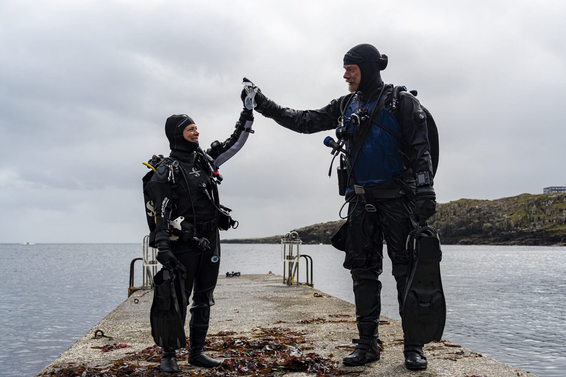 Diving team high-five moment in the Faroe Islands, celebrating a successful dive expedition